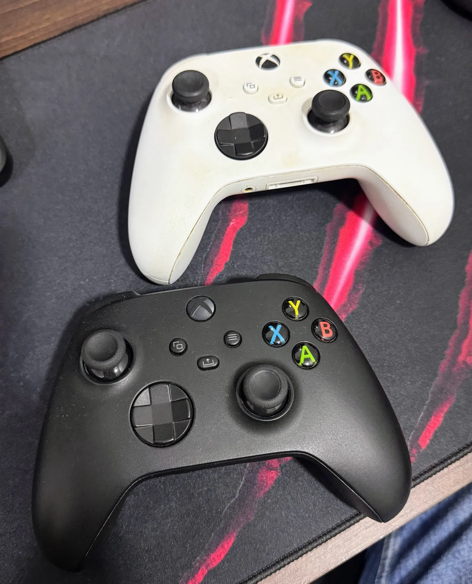 Dois controles de Xbox Series, um branco e um preto, lado a lado na mesa